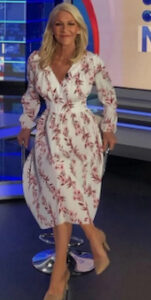 Jo Hall is pictured wearing a floral printed dress featuring a v-neckline and long sleeves