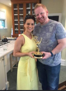 Lindsey Mastis and her husband pose for a photo with the Emmy Award